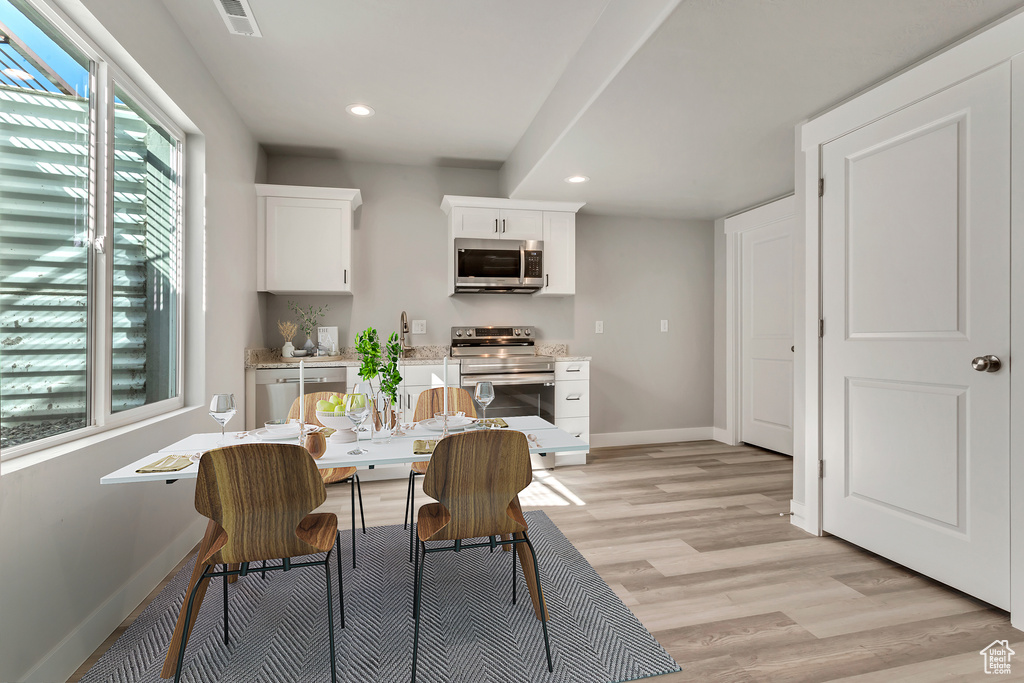 Kitchen with white cabinetry, stainless steel appliances, and light hardwood / wood-style floors