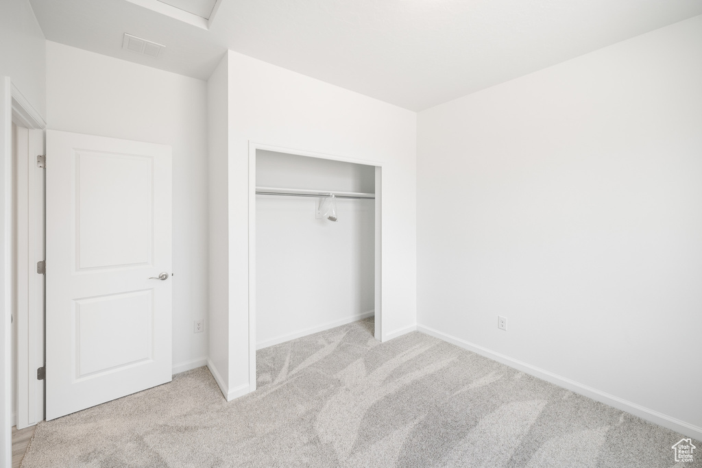 Unfurnished bedroom with light colored carpet and a closet