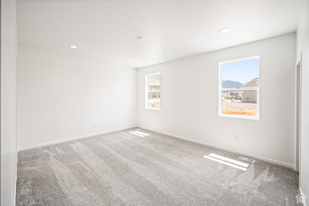 Empty room with a healthy amount of sunlight and carpet