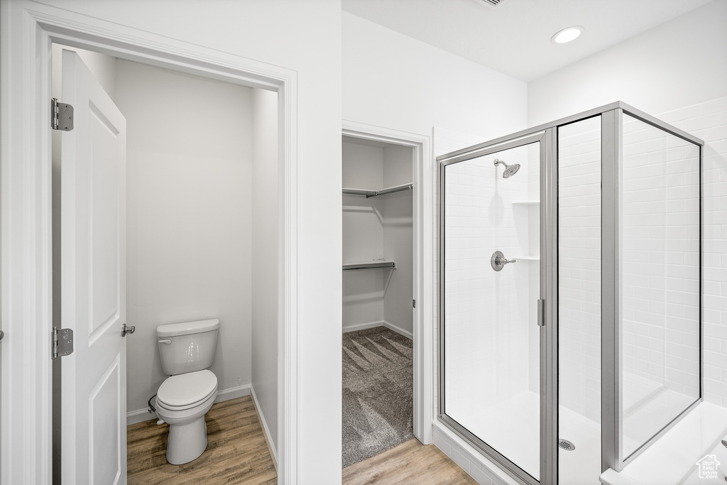 Bathroom featuring toilet, hardwood / wood-style floors, and a shower with shower door