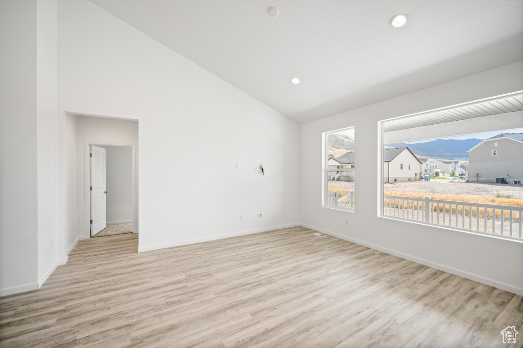 Spare room with light hardwood / wood-style floors and lofted ceiling