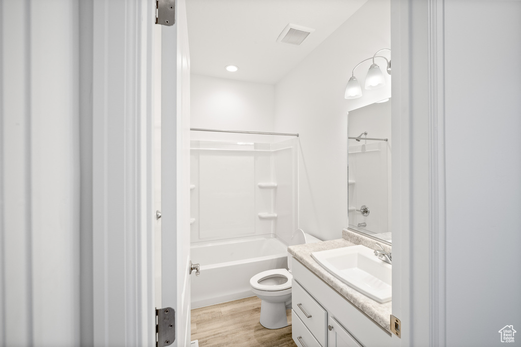 Full bathroom with toilet, shower / washtub combination, hardwood / wood-style floors, and vanity