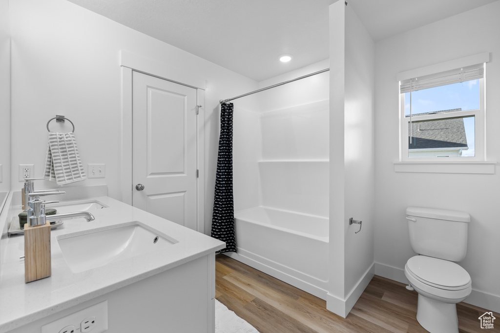 Full bathroom featuring vanity, shower / bath combo with shower curtain, hardwood / wood-style flooring, and toilet