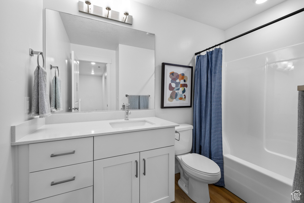 Full bathroom featuring vanity, toilet, hardwood / wood-style flooring, and shower / tub combo