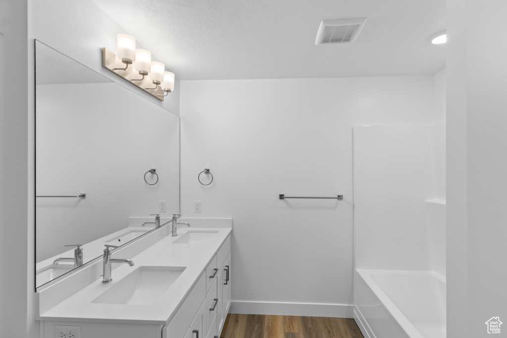 Bathroom featuring vanity, plus walk in shower, and wood-type flooring