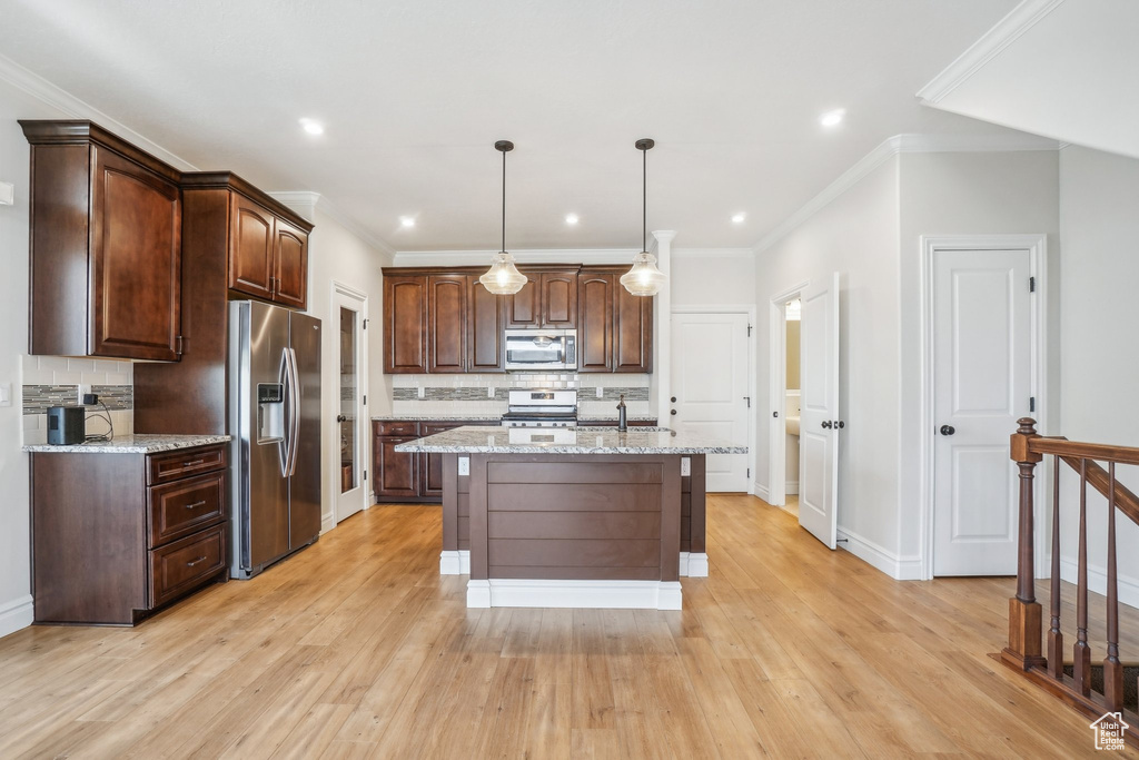 Kitchen featuring appliances with stainless steel finishes, tasteful backsplash, light stone countertops, and light wood-type flooring