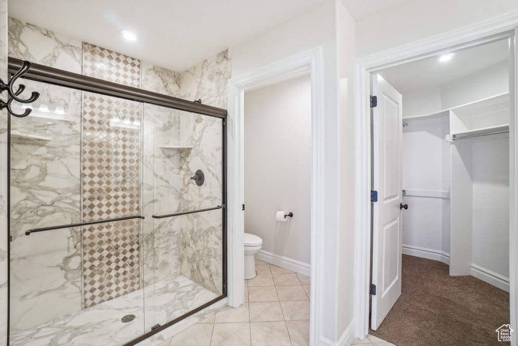 Bathroom featuring toilet, an enclosed shower, and tile patterned floors