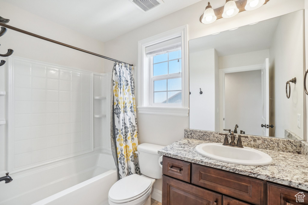 Full bathroom featuring toilet, shower / bath combo, and vanity