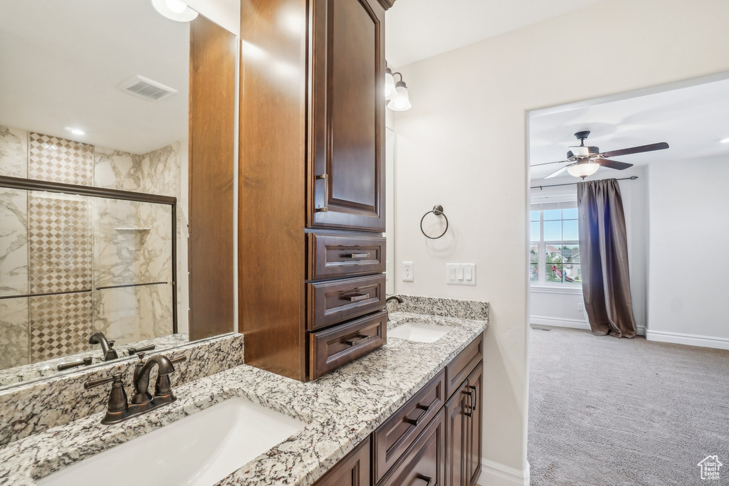 Bathroom featuring vanity, a shower with shower door, and ceiling fan