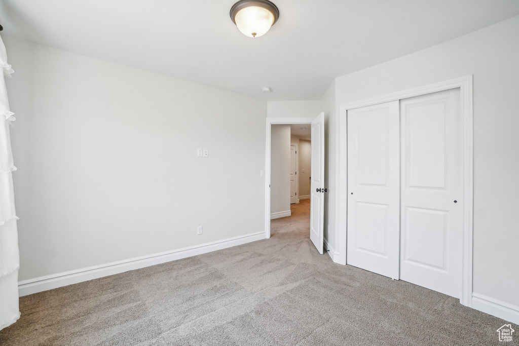 Unfurnished bedroom with light colored carpet and a closet