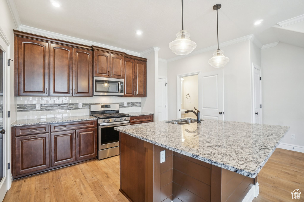 Kitchen with a center island with sink, sink, stainless steel appliances, and light wood-type flooring