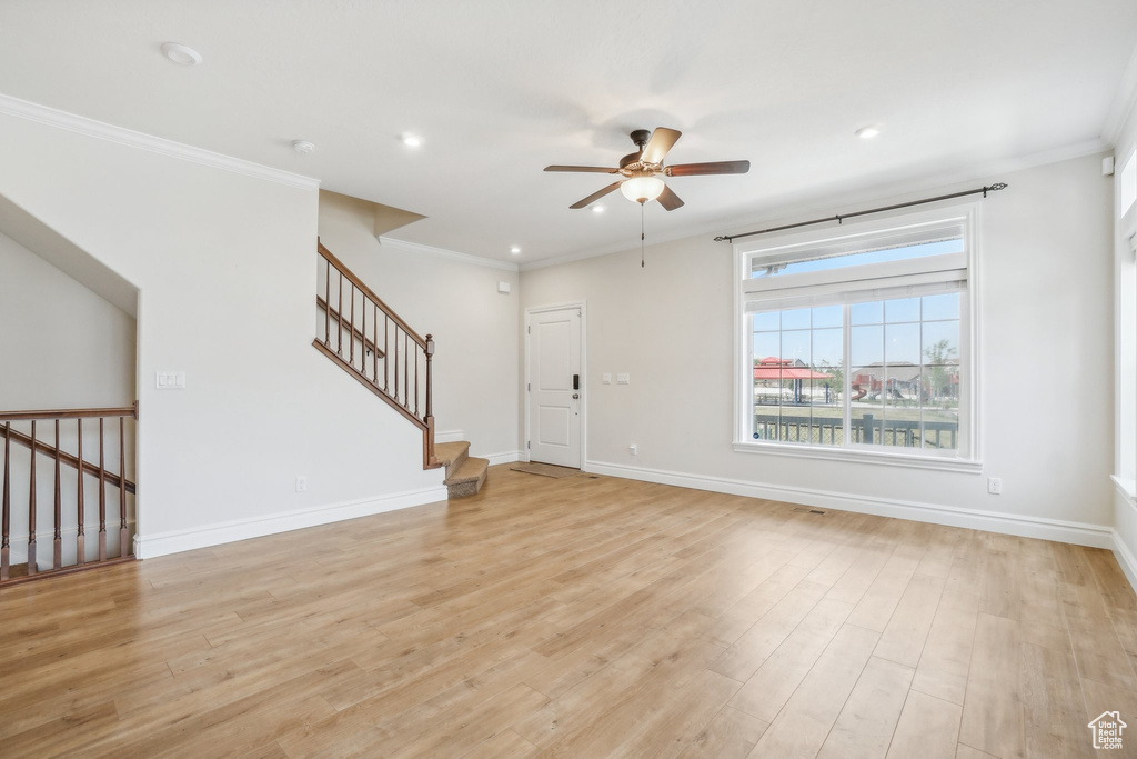 Unfurnished living room featuring crown molding, light wood-type flooring, and ceiling fan