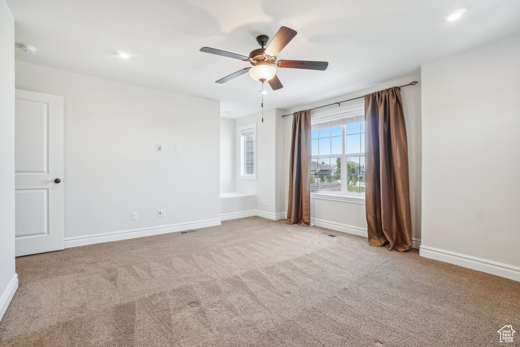 Carpeted spare room featuring ceiling fan