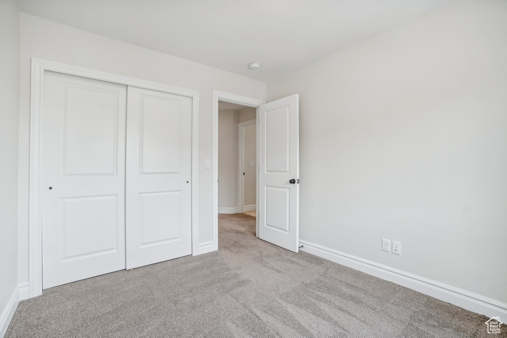 Unfurnished bedroom with light carpet and a closet