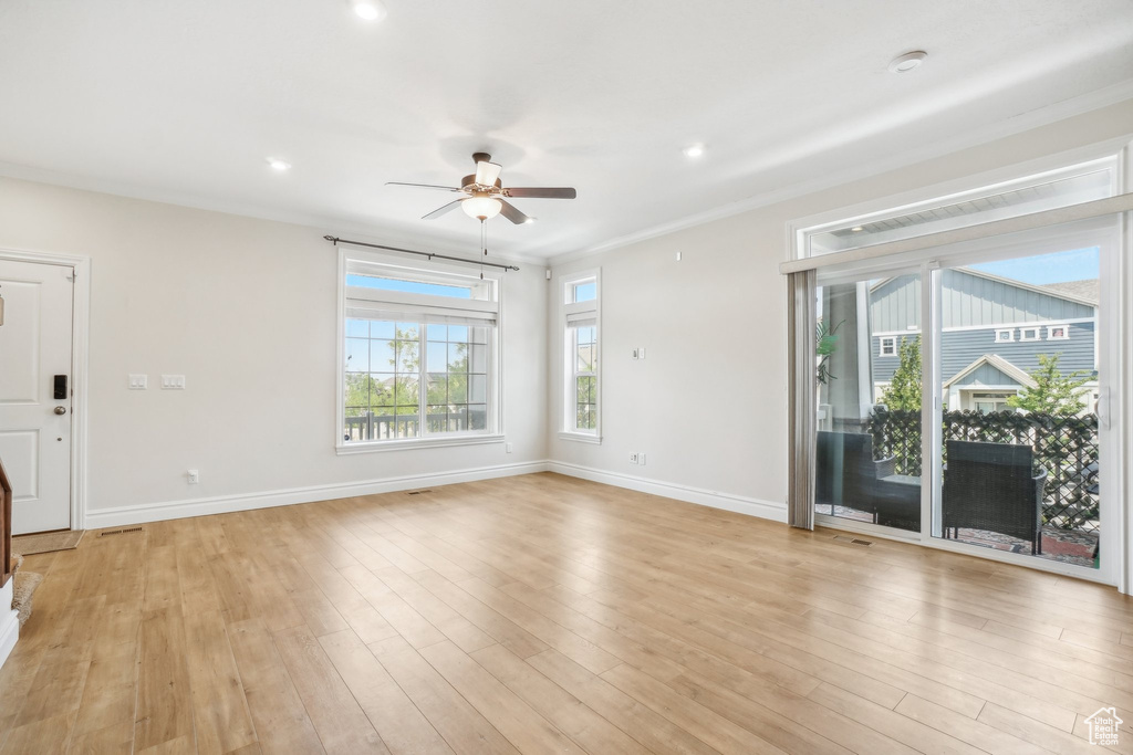 Unfurnished living room featuring ornamental molding, light wood-type flooring, and ceiling fan