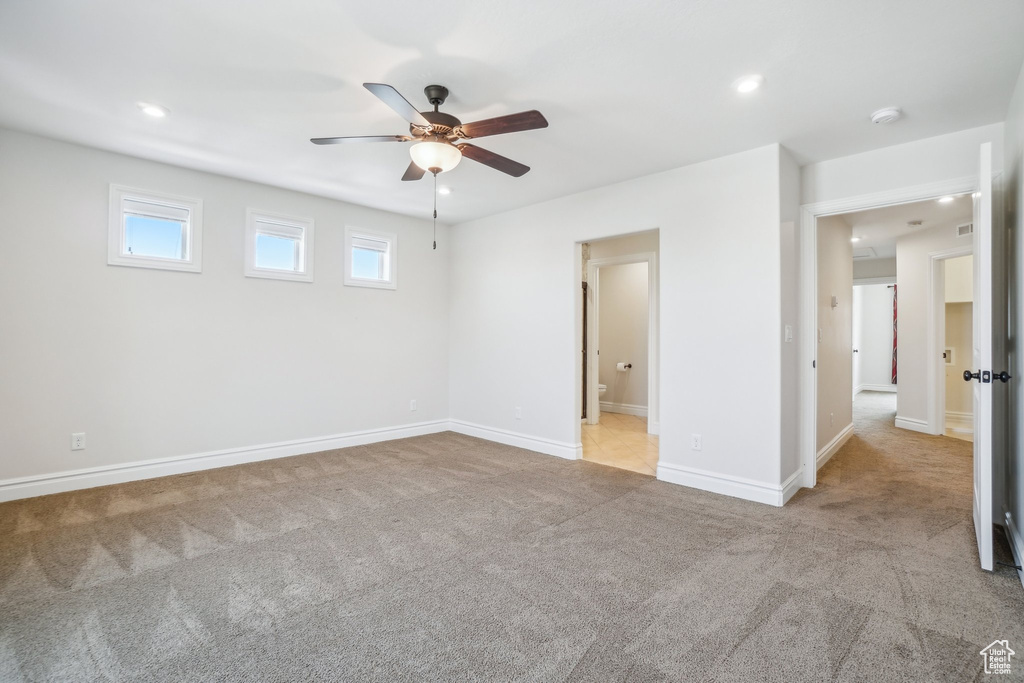 Interior space featuring light carpet, ensuite bathroom, and ceiling fan