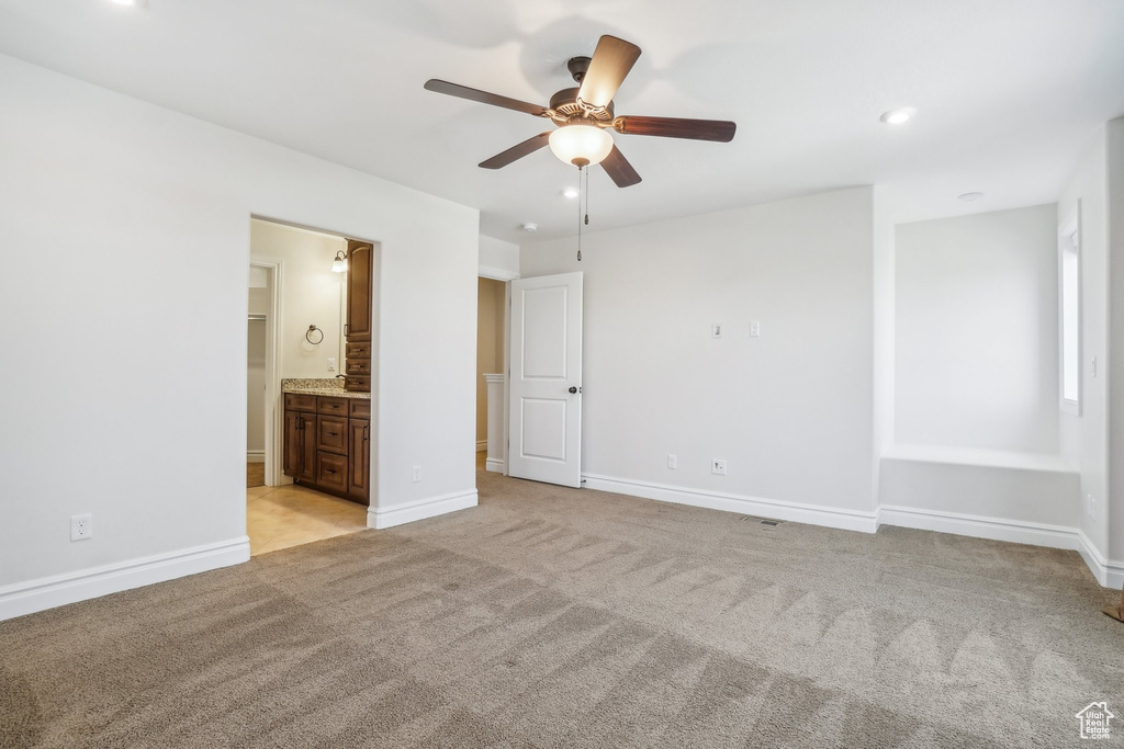 Unfurnished bedroom featuring connected bathroom, light colored carpet, and ceiling fan