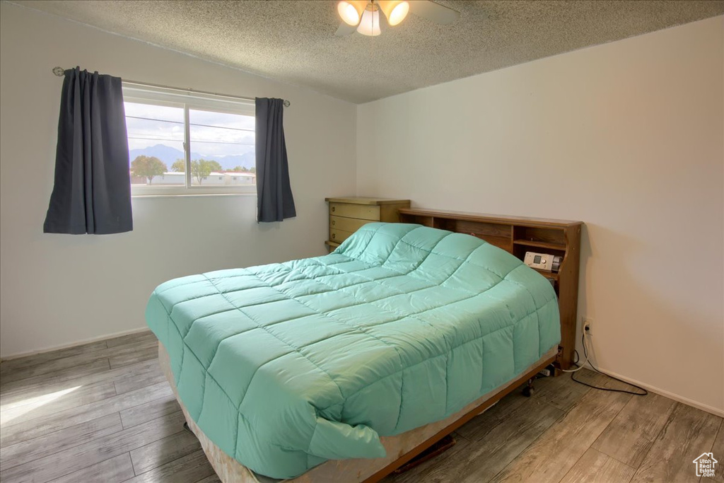 Bedroom featuring ceiling fan, wood-type flooring, and a textured ceiling