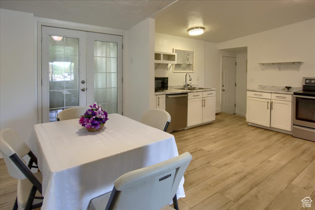 Dining room with a textured ceiling, sink, and light wood-type flooring