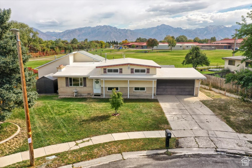 View of front of home with a mountain view and a front lawn