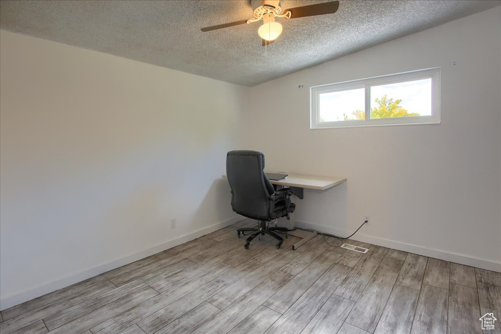 Unfurnished office with ceiling fan, a textured ceiling, and light hardwood / wood-style flooring