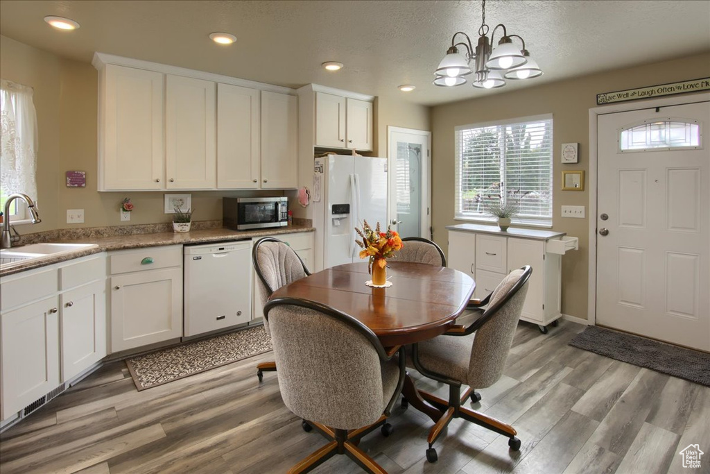 Dining area with sink, light hardwood / wood-style flooring, a textured ceiling, and an inviting chandelier