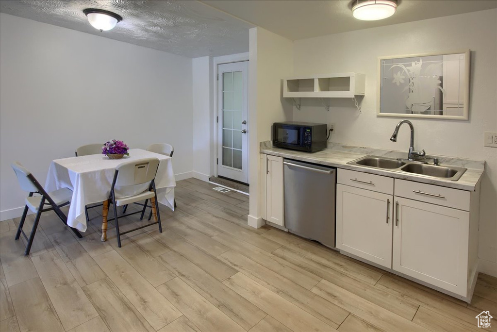 Kitchen with sink, stainless steel dishwasher, white cabinets, a textured ceiling, and light hardwood / wood-style floors