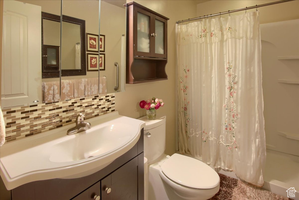 Full bathroom featuring vanity, toilet, decorative backsplash, and shower / tub combo