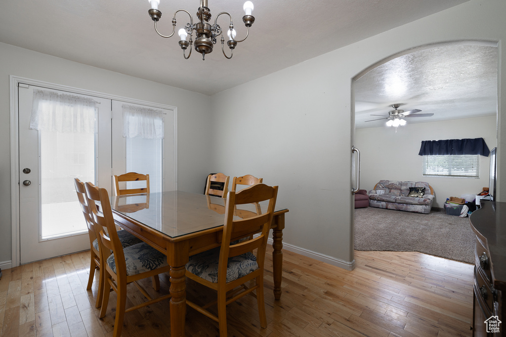 Dining area featuring light wood-type flooring and ceiling fan with notable chandelier