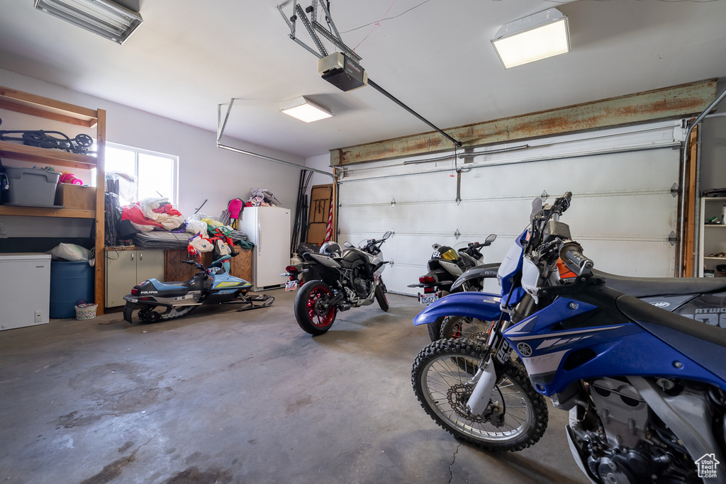 Garage featuring a garage door opener and white refrigerator