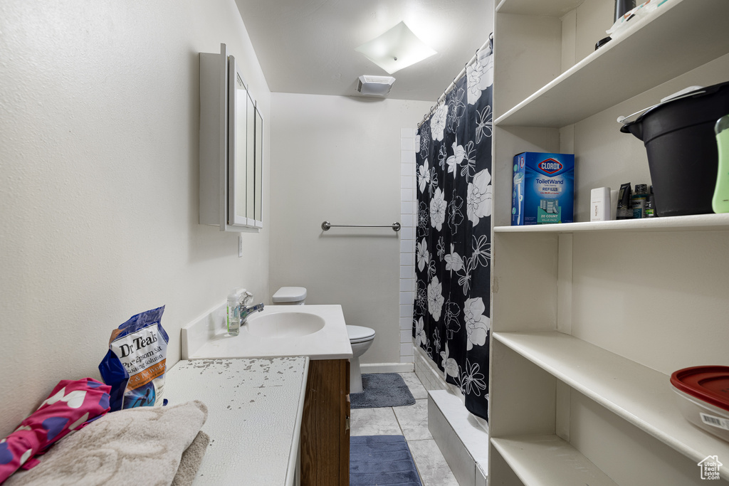 Bathroom with toilet, walk in shower, vanity, and tile patterned flooring