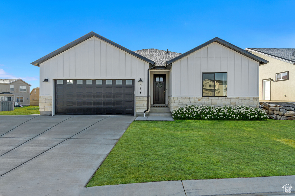 Modern inspired farmhouse with a front yard and a garage