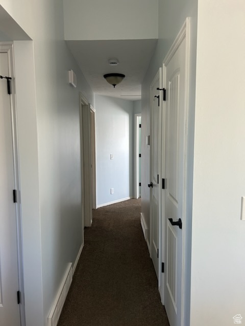 Hallway featuring dark carpet