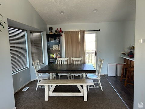 Dining area with vaulted ceiling and dark hardwood / wood-style floors