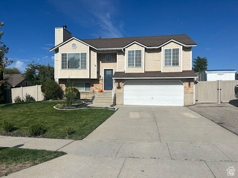 Raised ranch featuring a front lawn and a garage