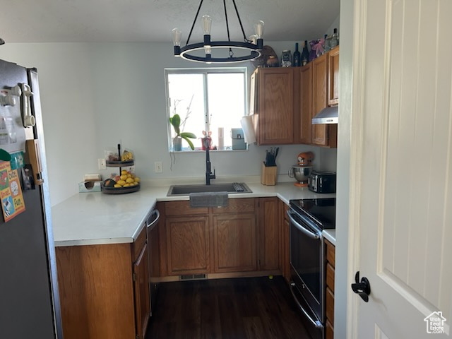 Kitchen with sink, stainless steel fridge, black / electric stove, a chandelier, and ventilation hood