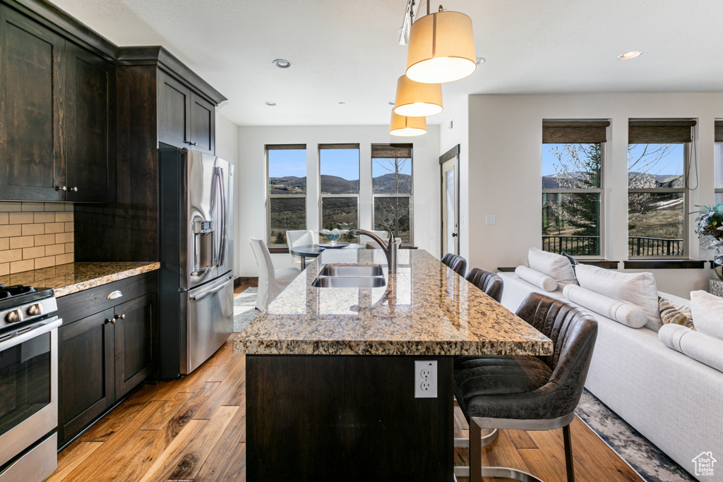 Kitchen featuring appliances with stainless steel finishes, a healthy amount of sunlight, sink, and an island with sink