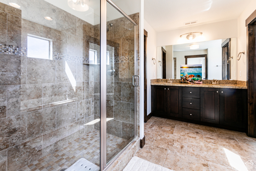 Bathroom featuring a shower with door and vanity