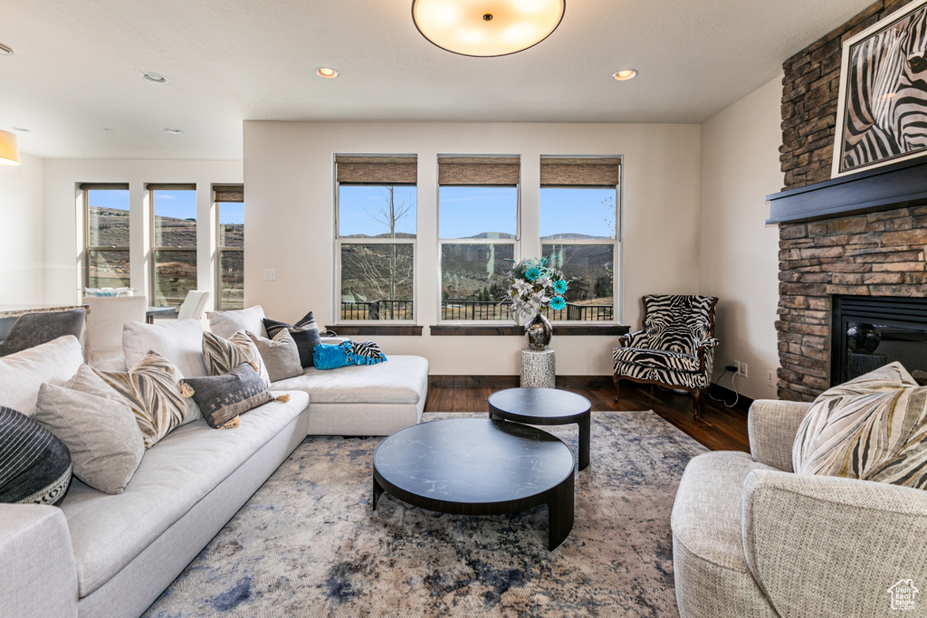 Living room with a mountain view, hardwood / wood-style flooring, and a stone fireplace