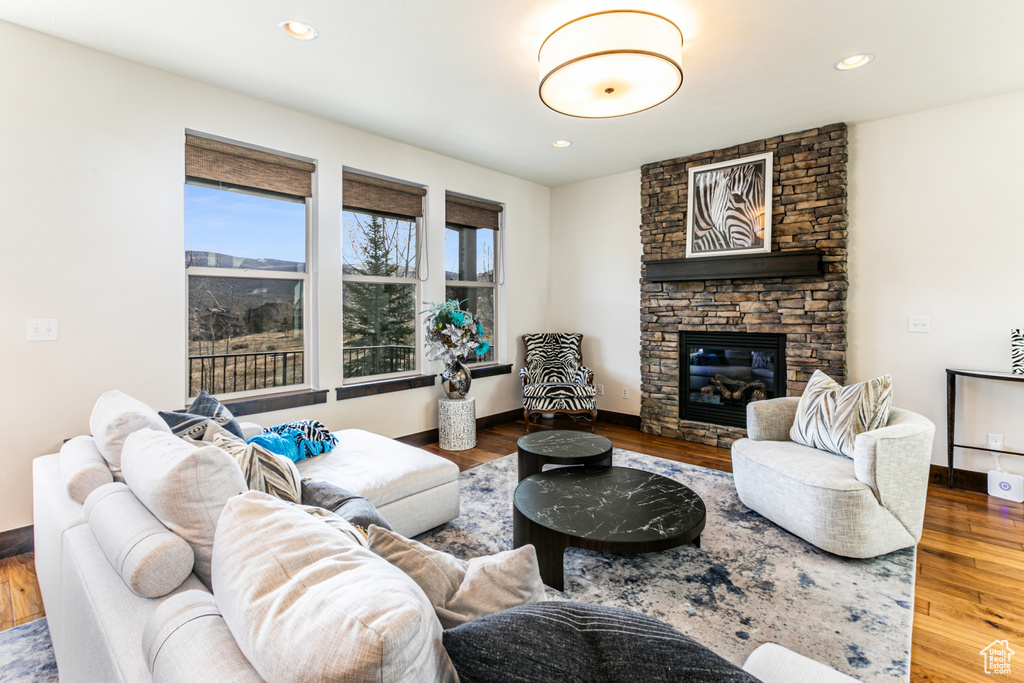 Living room with a stone fireplace and hardwood / wood-style floors