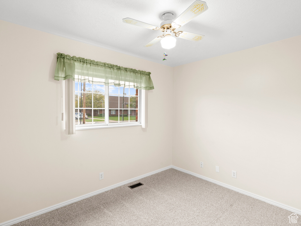 Unfurnished room featuring carpet floors and ceiling fan