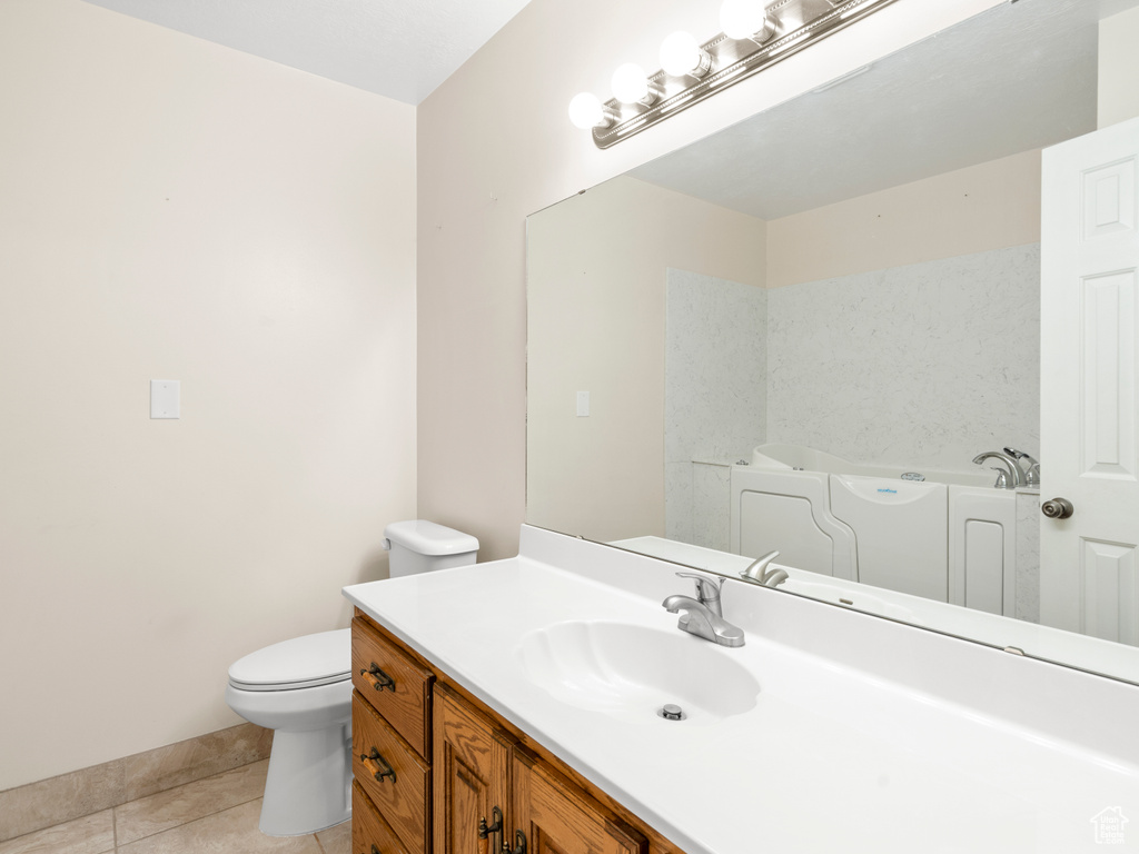 Bathroom featuring vanity, toilet, tile patterned flooring, and a bath