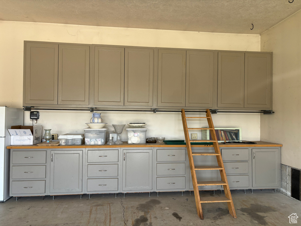 Kitchen with gray cabinets, a textured ceiling, and wooden counters