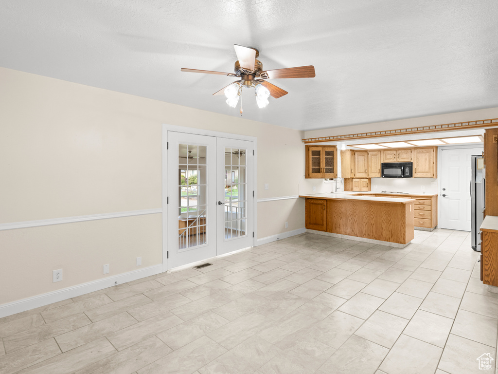 Kitchen featuring light tile patterned flooring, french doors, kitchen peninsula, stainless steel fridge, and ceiling fan