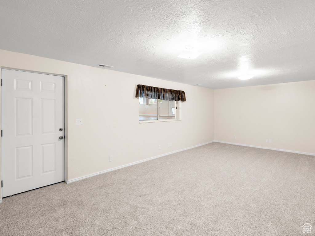 Carpeted empty room with a textured ceiling