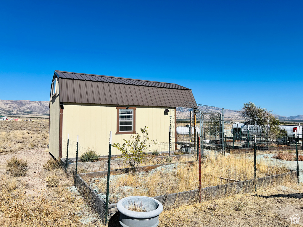 View of side of home with a mountain view and an outbuilding