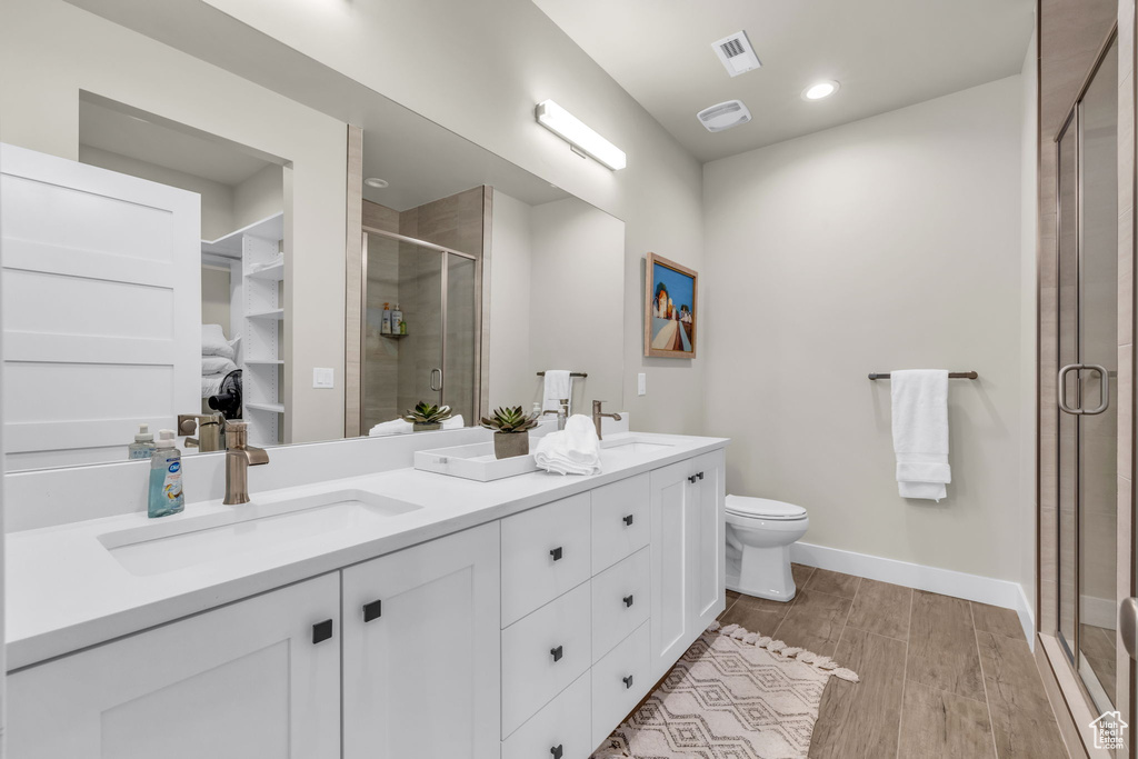 Bathroom with vanity, hardwood / wood-style floors, a shower with shower door, and toilet