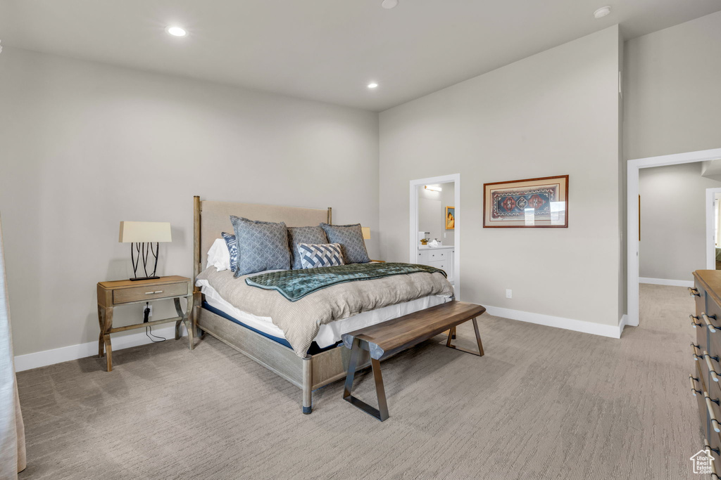 Carpeted bedroom with ensuite bath and a high ceiling