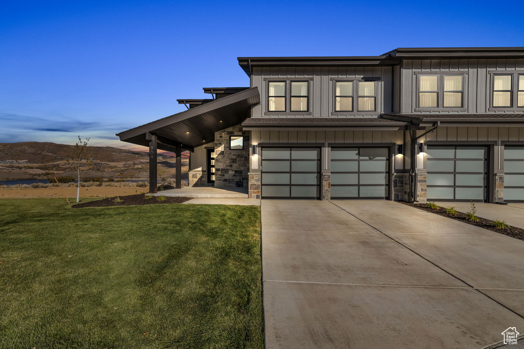 View of front of home featuring a yard, a mountain view, and a garage