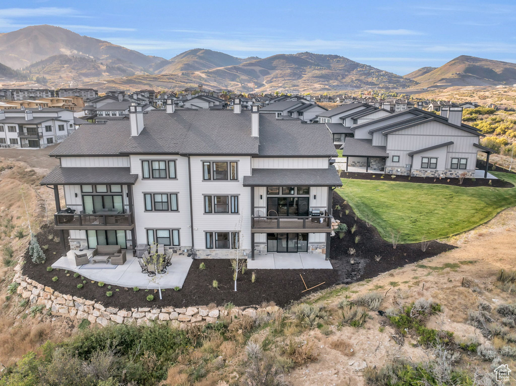 Rear view of house featuring an outdoor living space, a yard, a mountain view, and a patio